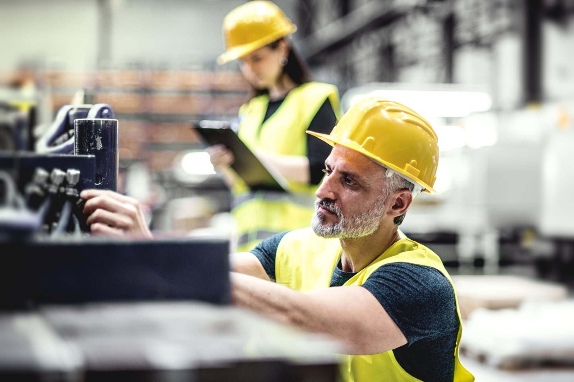 EHS man in focus in factory woman blur clipboard-scaled
